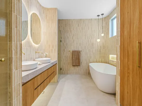 Salle de bains avec double vasque, miroirs ronds éclairés et baignoire îlot